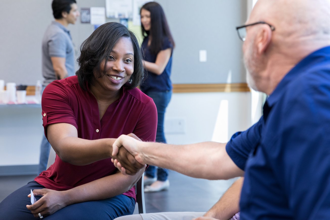 Female veteran shakes hands with male veterans before support group